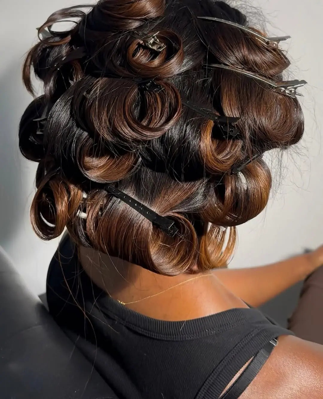 Person with styled hair in rollers against a neutral background