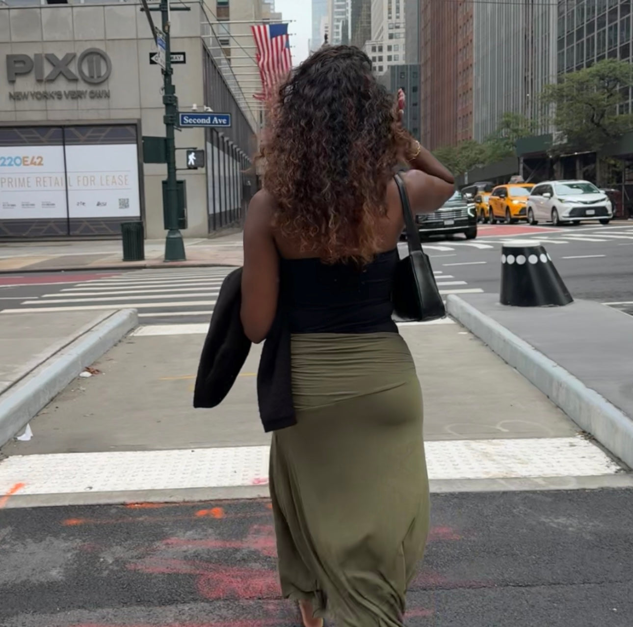 Woman taking a selfie on a city street with Pixio and American flags in the background