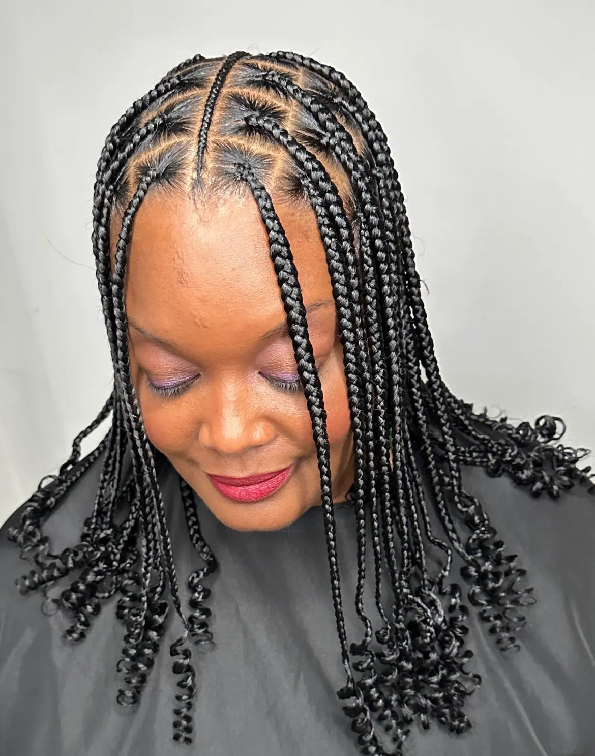 Woman with braided hair wearing a black salon cape.